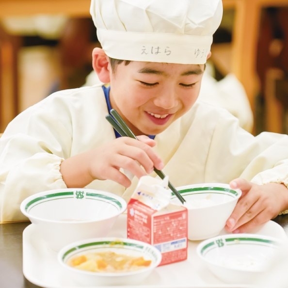 配膳した給食を運ぶ児童